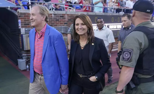 FILE - Texas Attorney General Ken Paxton, left, walks with his wife and Texas State Sen. Angela Paxton on the sideline before an NCAA college football game between Navy and SMU in Dallas, Oct. 14, 2022. (AP Photo/LM Otero, File)