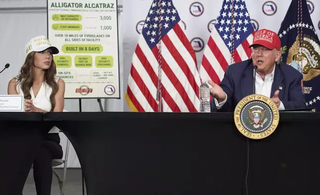 Homeland Security Secretary Kristi Noem listens as President Donald Trump speaks during a roundtable at "Alligator Alcatraz," a new migrant detention facility at Dade-Collier Training and Transition facility, Tuesday, July 1, 2025, in Ochopee, Fla. (AP Photo/Evan Vucci)