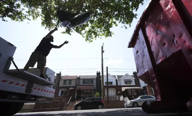 A man tosses trash at a garbage collection site, Thursday, July 3, 2025, in Philadelphia. (AP Photo/Matt Slocum)