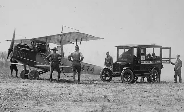 In this photo provided by the National Archives and Records Administration, mail is loaded onto a Curtiss JN-4H "Jenny" biplane, May 15, 1918, at Bustleton Field near Philadelphia, while U.S. Army personnel look on. (National Archives and Records Administration via AP)