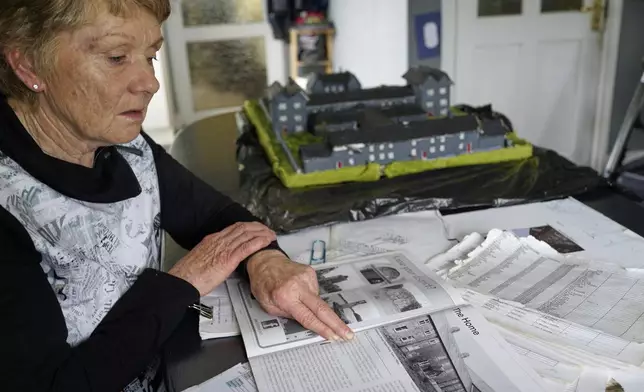 Catherine Corless, who revealed that remains of nearly 800 dead infants from a mother and baby home in Tuam, Ireland, were unaccounted for and likely buried in a mass grave, reviews her records at her home outside Tuam on Tuesday, July 8, 2025. (AP Photo/Brian Melley)