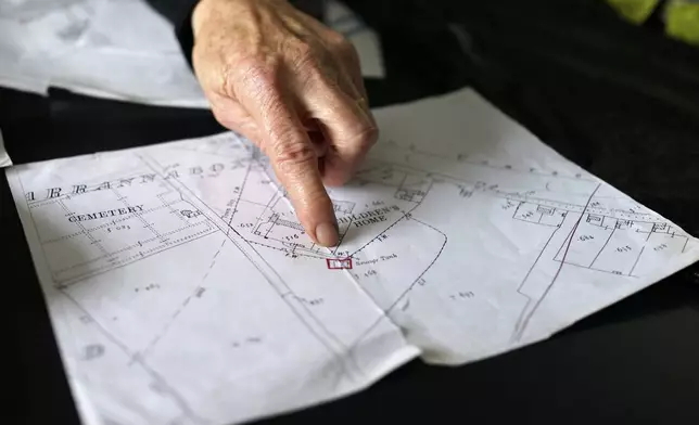 Catherine Corless, who revealed that remains of nearly 800 dead infants from a mother and baby home in Tuam, Ireland, were unaccounted for and likely buried in a mass grave, points on a map at her home outside Tuam on Tuesday, July 8, 2025. (AP Photo/Brian Melley)