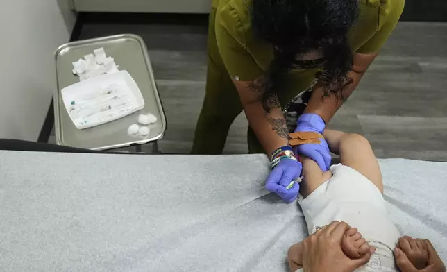 Medical assistant Citlalli Llamas, top, administers a round of vaccines to a 16-month-old boy at a CommuniCARE+OLE clinic Thursday, June 26, 2025, in Davis, Calif. (AP Photo/Godofredo A. Vásquez)