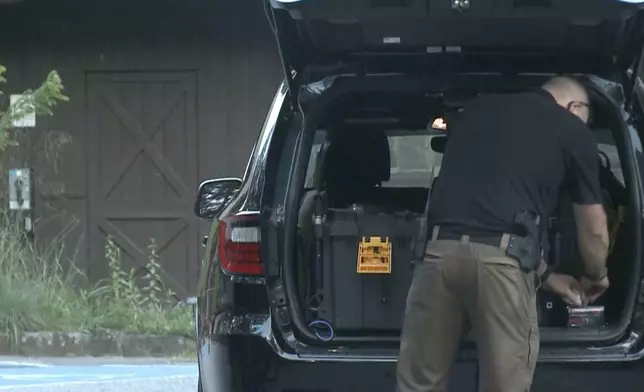 In this image made from video taken on Saturday, July 26, 2025, provided by KHBS/KHOG, law enforcement officers investigate the deaths of a couple who were attacked while on a wooded walking trail with their two young daughters at Devil's Den State Park in West Fort, Ark. (KHBS/KHOG via AP)