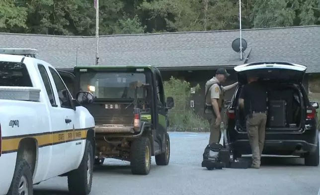 In this image made from video taken on Saturday, July 26, 2025, provided by KHBS/KHOG, law enforcement officers investigate the deaths of a couple who were attacked while on a wooded walking trail with their two young daughters at Devil's Den State Park in West Fort, Ark. (KHBS/KHOG via AP)