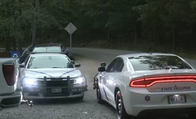 In this image made from video taken on Saturday, July 26, 2025, provided by KHBS/KHOG, Law enforcement officers investigate the deaths of a couple who were attacked while on a wooded walking trail with their two young daughters at Devil's Den State Park in West Fort, Ark. (KHBS/KHOG via AP)