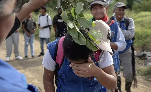 A child is gently splashed with water, a ritual meant to protect them, July, 19, 2025, in the Lopez Adentro reserve in Caloto, Colombia. (AP Photo/Nadège Mazars)