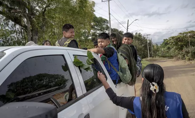Children are gently splashed with water, a ritual meant to protect them, on July, 19, 2025, in the Lopez Adentro reserve in Caloto, Colombia. (AP Photo/Nadège Mazars)
