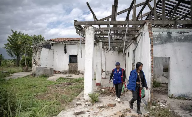 Part of the children's semillero, a school that prepares the next generation to protect their ancestral land, walk near the home of a former sugarcane landlord on reclaimed land while putting up signs in the area on July, 19, 2025, in the Lopez Adentro reserve in Caloto, Colombia. (AP Photo/Nadège Mazars)