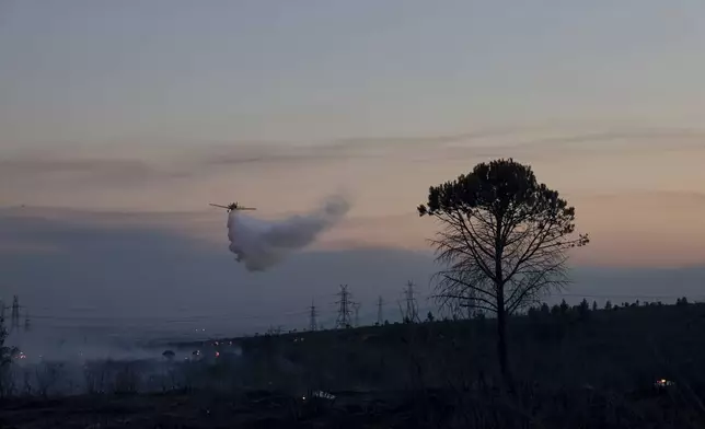 An aircraft drops water over a fire, in the northwestern suburb of Kryoneri, in Athens, Greece, Saturday, July 26, 2025. (AP Photo/Yorgos Karahalis)