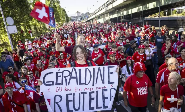 Two young fans hold a poster for Switzerland player Geraldine Reuteler with the words "You are a mega role model" as they walk towards the stadium for the Euro 2025, group A, soccer match between Finland and Switzerland at Stade de Geneve in Geneva, Switzerland, Thursday, July 10, 2025. (Jean-Christophe Bott/Keystone via AP)