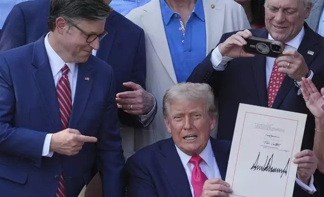 House Speaker Mike Johnson of La., points to President Donald Trump after he signed his signature bill of tax breaks and spending cuts at the White House, Friday, July 4, 2025, in Washington, surrounded by members of Congress. (AP Photo/Evan Vucci)