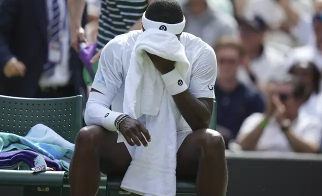 Frances Tiafoe of the U.S. wipes his face during a change of ends break as he plays Cameron Norrie of Britain during their second round men's singles match at the Wimbledon Tennis Championships in London, Wednesday, July 2, 2025. (AP Photo/Alastair Grant)