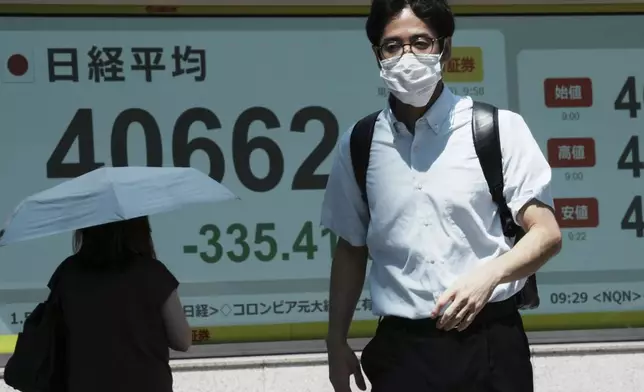 A person walks in front of an electronic stock board showing Japan's Nikkei index at a securities firm Tuesday, July 29, 2025, in Tokyo. (AP Photo/Eugene Hoshiko)