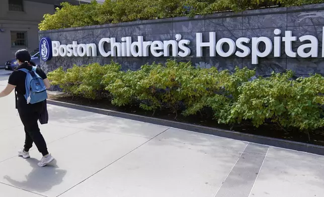 FILE — A woman walks past a sign outside the Boston Children's Hospital, Aug. 18, 2022, in Boston. (AP Photo/Charles Krupa, File)