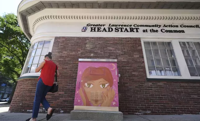 A woman walks toward the Greater Lawrence Community Action Council office where immigrants receive health assistance, June 25, 2025, in Lawrence, Mass. (AP Photo/Charles Krupa)