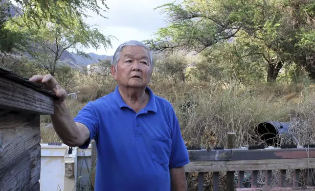 Calvin Endo stands in his backyard discussing his concerns about tall grass that grows brown during wildfire season behind his home on Saturday, July 5, 2025, in Waianae, Hawaii. (AP Photo/Jennifer Sinco Kelleher)