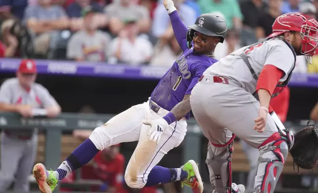 Colorado Rockies' Adael Amador, left, scores on a single hit by Mickey Moniak as St. Louis Cardinals catcher Pedro Pagés, right, waits for the throw in the third inning of a baseball game Monday, July 21, 2025, in Denver. (AP Photo/David Zalubowski)