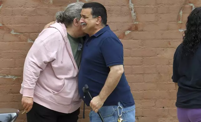 A unidentified man, right, appears emotional while embracing a resident of the Gabriel House assisted living facility, left, in Fall River, Mass., outside a temporary shelter, Monday, July 14, 2025, in Fall River, following a fire at the Gabriel House that started late Sunday and resulted in multiple fatalities. (AP Photo/Steven Senne)