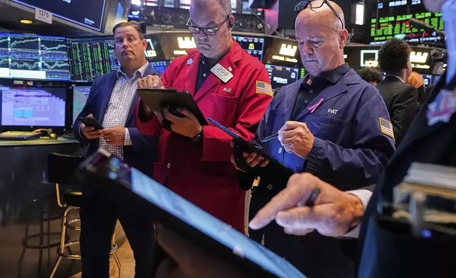 Traders William Lawrence, second left, and Patrick Casey, third left, work on the floor of the New York Stock Exchange, Friday, July 18, 2025. (AP Photo/Richard Drew)