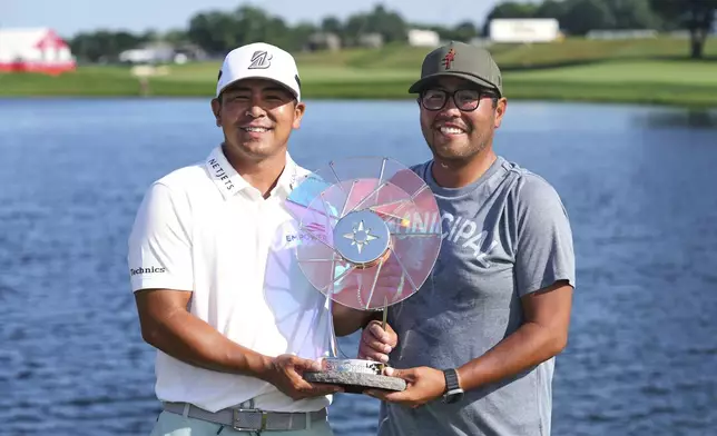 Kurt Kitayama, left, and his caddie, Daniel Kitayama, hold their trophy after winning the 3M Open golf tournament at the Tournament Players Club Sunday, July 27, 2025, in Blaine, Minn. (AP Photo/Abbie Parr)