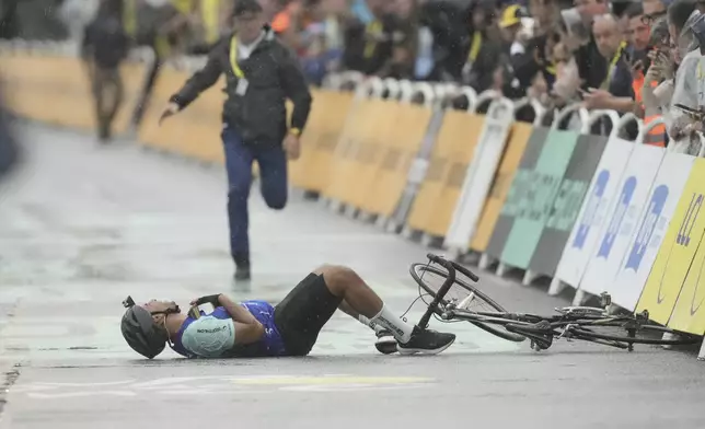 A man who was riding to the finish line lies on the asphalt after being blocked by security, during the seventeenth stage of the Tour de France cycling race over 160.4 kilometers (99.7 miles) with start in Bollene and finish in Valence, France, Wednesday, July 23, 2025. (AP Photo/Thibault Camus)