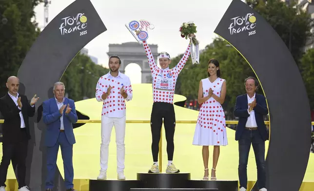 Slovenia's Tadej Pogacar, holds the award for the best climber as he celebrates during the presentation ceremony for the Tour de France on the Champs-Elysees in Paris, France, Sunday, July 27, 2025. (Bernard Papon, Pool Photo via AP)
