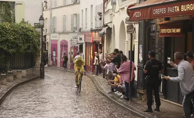 Slovenia's Tadej Pogacar, wearing the overall leader's yellow jersey, pedals at the Place de Tertre in the Montmartre district, during the last stage of the Tour de France cycling race between Mantes-la-Ville and Paris, Sunday, July 27, 2025 in Paris (AP Photo/Thomas Padilla)