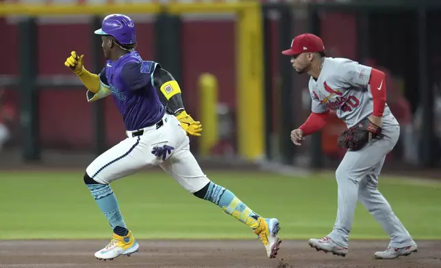 Arizona Diamondbacks' Geraldo Perdomo, left, runs past St. Louis Cardinals first baseman Willson Contreras (40) on his way to third base with a triple during the first inning of a baseball game Friday, July 18, 2025, in Phoenix. (AP Photo/Ross D. Franklin)