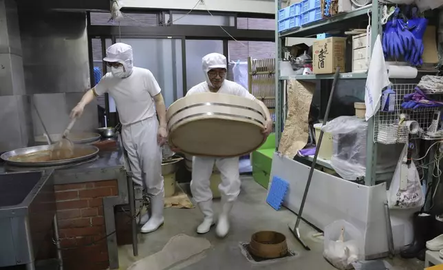 Nobuo Kobayashi, right, and his son Yoshihiro Kobayashi prepare a traditional Japanese dish called tsukudani, at their store in the Tsukuda area of Tokyo on June 18, 2025. (AP Photo/Yuri Kageyama)