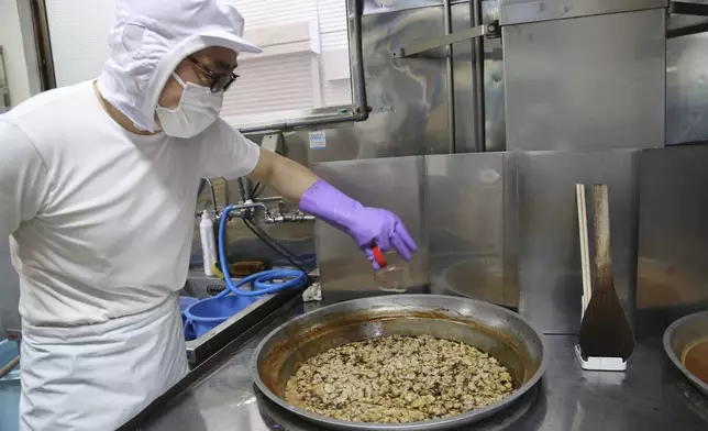 Yoshihiro Kobayashi prepares tsukudani, a Japanese preserved food, in Tsukuda, Tokyo on June 18, 2025. (AP Photo/Yuri Kageyama)