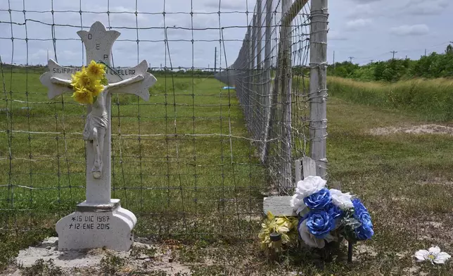 A grave marker in Spanish and flowers are placed at the corner of a farm where reportedly workers have been afraid to show up to work due to fears of ICE raids, in the Rio Grande Valley, Thursday, June 19, 2025, near Weslaco, Texas. (AP Photo/Jacquelyn Martin)