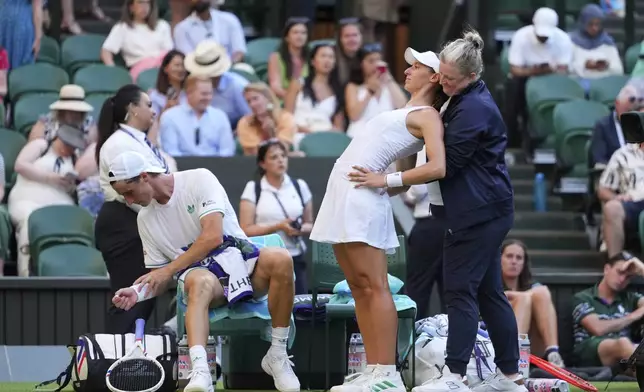 Joe Salisbury of Britain watches as Luisa Stefani of Brazil gets medical assistance during the mixed doubles final match against Sem Verbeek of Netherland and Katerina Siniakova of Czech Republic at the Wimbledon Tennis Championships in London, Thursday, July 10, 2025.(AP Photo/Kirsty Wigglesworth)