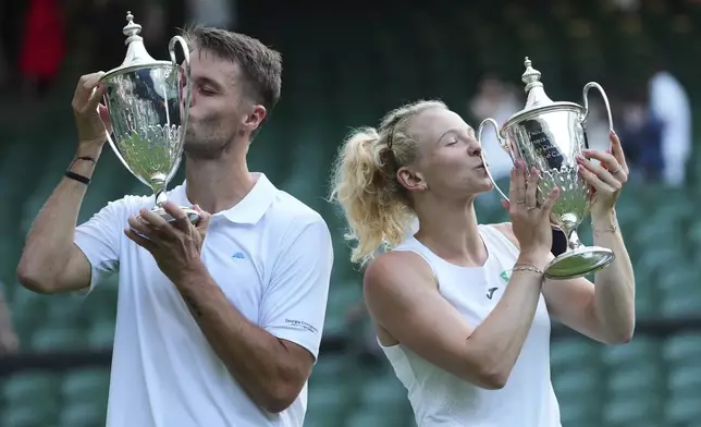 Winner Sem Verbeek of the Netherlands, left, and Katerina Siniakova of Czech Republic, right, kiss the trophy after winning the mixed doubles final match against Joe Salisbury of Britain and Luisa Stefani of Brazil at the Wimbledon Tennis Championships in London, Thursday, July 10, 2025.(AP Photo/Kirsty Wigglesworth)