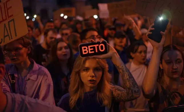A woman holds a phone with a sign reads "Veto" during the protest against the law aimed towards regulations of anti-corruption institutions in central Kyiv, Ukraine, Tuesday, July 22, 2025. (AP Photo/Alex Babenko)