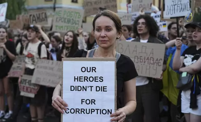 A woman holds a banner during a protest against a law targeting anti-corruption institutions in central Kyiv, Ukraine, Wednesday, July 23, 2025. (AP Photo/Efrem Lukatsky)