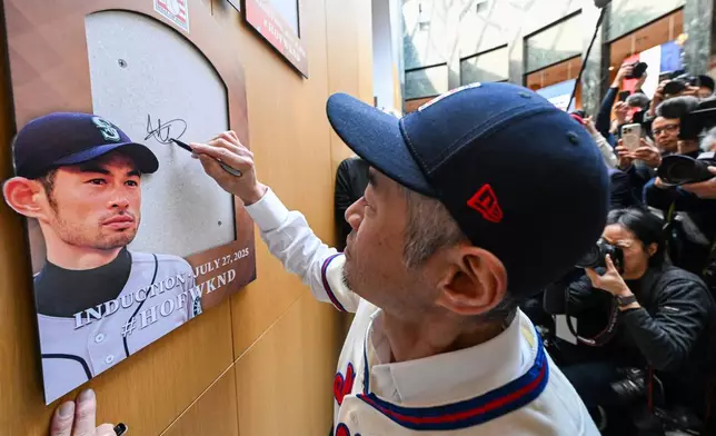 FILE - Newly-elected Baseball Hall of Fame member Ichiro Suzuki signs the backer board where his plaque will hang during a news conference Thursday, Jan. 23, 2025, in Cooperstown, N.Y. (AP Photo/Hans Pennink, File)