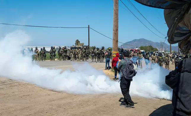 Federal immigration agents toss tear gas at protesters during a raid in the agriculture area of Camarillo, Calif., Thursday, July 10, 2025. (AP Photo/Michael Owen Baker)