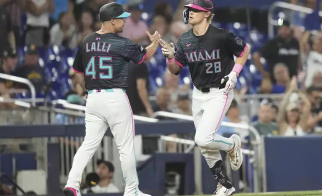 Miami Marlins' Kyle Stowers (28) passes third base coach Blake Lalli (45) after hitting a solo home run during the third inning of a baseball game against the Milwaukee Brewers, Saturday, July 5, 2025, in Miami. (AP Photo/Lynne Sladky)