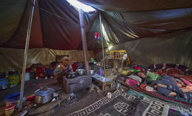 Kunzang Angmo, center, prepares food as her son Phunsukh Chondon, right, sleeps inside a government provided tent in Korzak village, Ladakh, India, Monday, July 7, 2025. (AP Photo/ Dar Yasin )