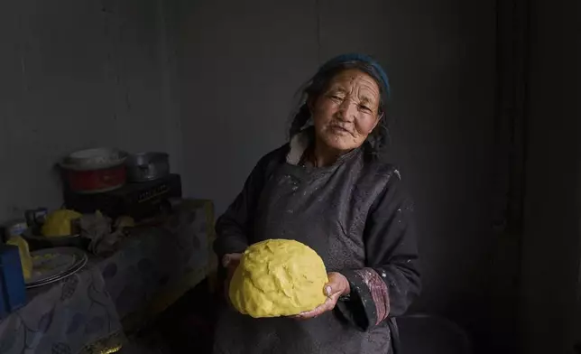 Kunzias Dolma, poses for a photograph with butter made from yak milk inside a plastic shelter provided by the government in Tsoltak village, Ladakh, India, Tuesday, July 8, 2025. (AP Photo/Dar Yasin)