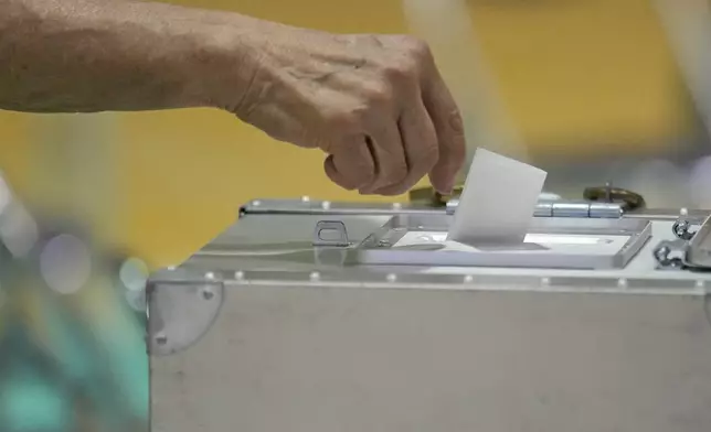 A voter casts a ballot in the upper house elections at a polling station Sunday, July 20, 2025, in Tokyo. (AP Photo/Eugene Hoshiko)