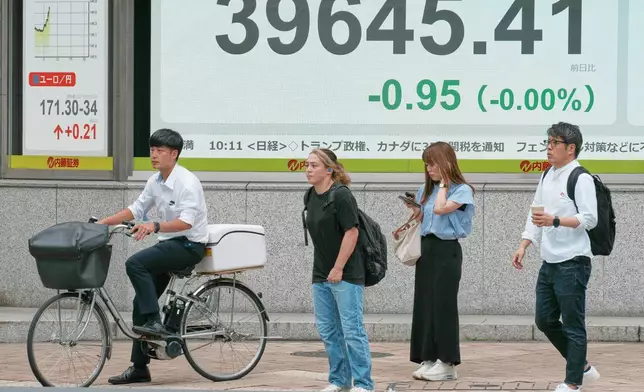 People stand in front of an electronic stock board showing Japan's Nikkei index at a securities firm Friday, July 11, 2025, in Tokyo. (AP Photo/Eugene Hoshiko)