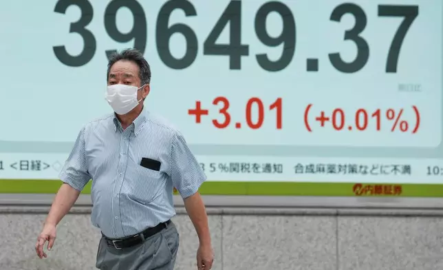 A person walks in front of an electronic stock board showing Japan's Nikkei index at a securities firm Friday, July 11, 2025, in Tokyo. (AP Photo/Eugene Hoshiko)