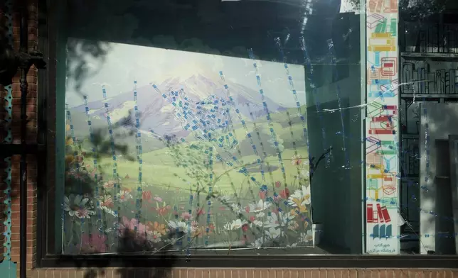 TThe front window of a well-known bookstore cracked after an explosion hit a nearby military site just behind the shop, in Tehran, Iran, Tuesday, June 24, 2025. Staff taped the glass to prevent further damage, creating the outline of Iran over a mural of Mount Damavand, a national symbol of resilience. (AP Photo)