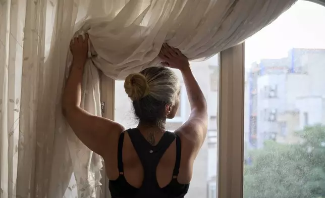 Maryam, who has the word "Iran" tattooed on the back of her neck, looks out the window of her home in Tehran, Iran, Wednesday, June 25, 2025. She lives alone with her daughter, Mastaneh, just a few blocks from the site of a key explosion during the war.(AP Photo)