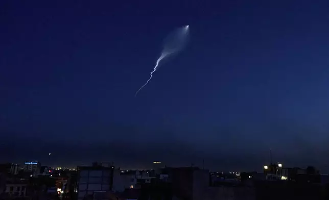 The trail of a missile launched by Iran is visible across the sky in Tehran, Iran, Wednesday, June 18, 2025. Most of the city's lights were off, some areas had been evacuated, and others remained dark intentionally. (AP Photo)