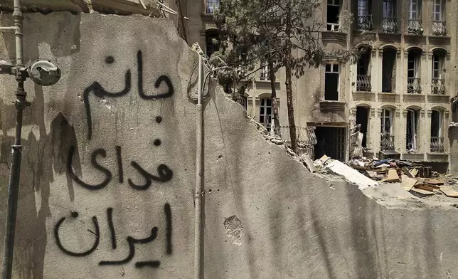 The phrase "My life for Iran" is spray-painted on the outer wall of a residential building heavily damaged by a missile strike in Tehran, Iran, Friday, June 27, 2025. (AP Photo)
