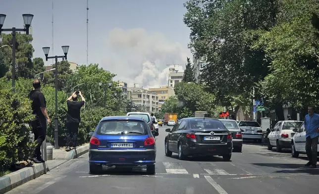 With their cellphones, residents take pictures of smoke rising from an Israeli strike in Tehran, Iran, Monday, June 23, 2025. Repeated explosions echoed across the city as plumes of smoke rose from multiple locations.(AP Photo)