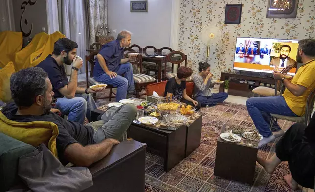 A group of friends gathers for dinner while following the latest updates on the Iran-Israel conflict in Tehran, Iran, Monday, June 23, 2025. Between bites, they keep their eyes on the TV for any news. (AP Photo)